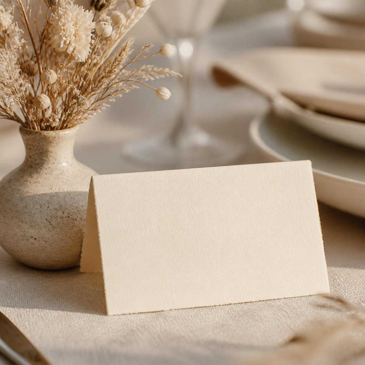 A place card resting on a linen wedding table beside dried flowers